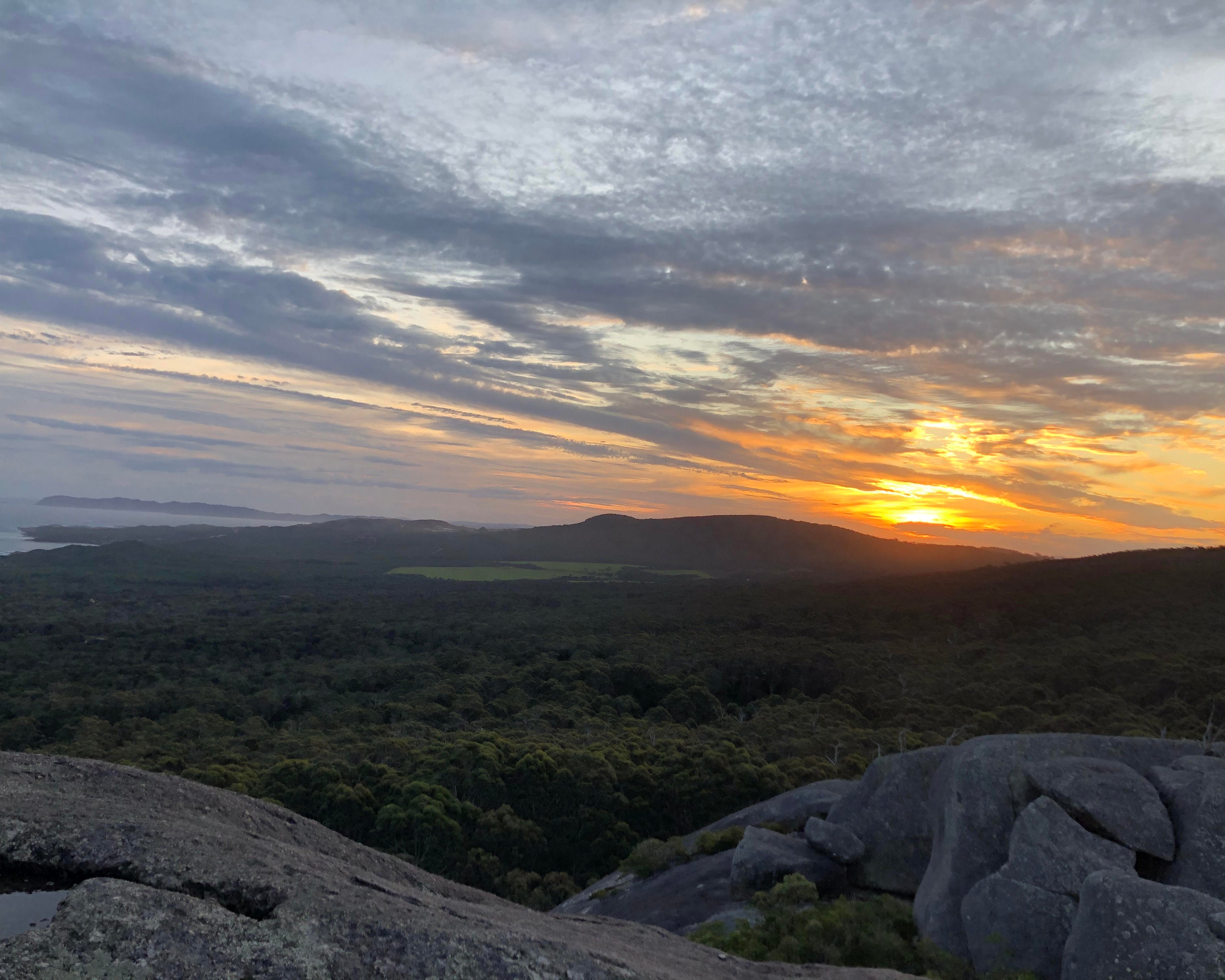 Sunset over a landscape with clouds and a rocky foreground